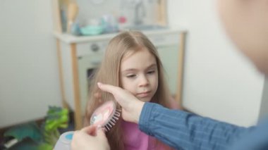 Bir insan sıcak, davetkar bir odada genç bir kızın uzun saçlarını tarar. Kız sakince oturur, güzel saçlarını göstererek nazikçe şekillenir..