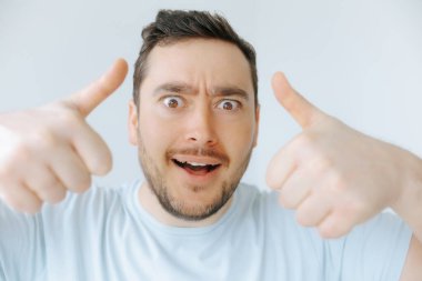 Neşeli bir ifadesi olan bir adam, kapalı bir ortamda coşku ve pozitifliği iki parmakla ifade eder. Parlak ışık neşeli atmosferi güçlendirir.