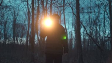 Geceleri ormanda yalnız bir figür yürür, el feneri bir şey ararken karanlığın içinden geçen ılık bir parıltı saçar..