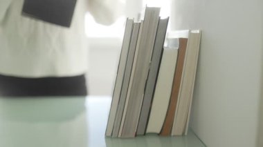 Tahta bir masanın üzerinde bir yığın kitap, yeni bir el ile, okumanın, eğitimin ve entelektüel gelişimin özünü yakalıyor..