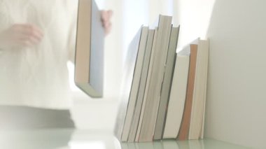 Bir el, öğrenmeyi ve düzeni sembolize eden yığına bir kitap ekler. Okuma, öğrenme ve edebiyat koleksiyonu yapma zevkini vurgulamak.