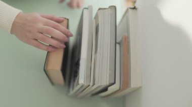 El ele tutuştuğumuz düşünceli bir an masadaki kitap seçiminin üzerinde duruyor, okuma ve keşfetme tutkusunu somutlaştırıyor..