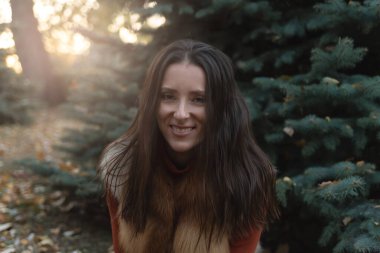 Hassas ve duyarlı bir kadının portresi bir sonbahar manzarasının arka planına karşı. Parkta sonbahar yaprakları, köknar ağacı, şapka, güneş ışığı