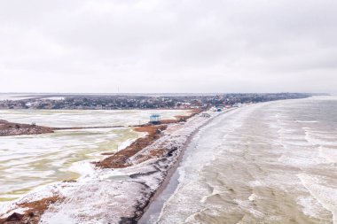 Deniz ve nehir arasında tükür. Açık deniz fırtınasının arka planına karşı gri kış günü