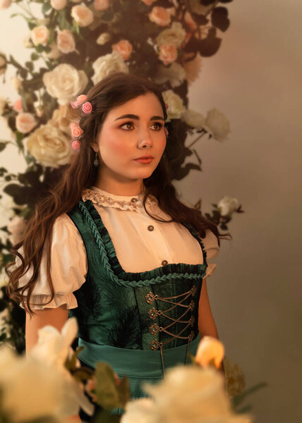 Молодая крестьянка, стоящая в саду с цветами в баварском платье XIX века.