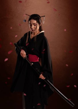 Japon kadın samuraylar kimono giyiyorlar ve kahverengi arka planda katana tutuyorlar ve çiçek yaprakları. Japon kültürü