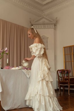 Uzun saçlı genç ve güzel bir kadın mutfakta çay içiyor. 19. yüzyıl. Eski