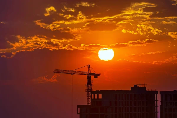 建設中の建物の黒いシルエットと太陽とオレンジの夕日に対するクレーン 街の夜 劇的な曇りの空 エレバン アルメニア テキストのための完璧なカラフルな背景 — ストック写真