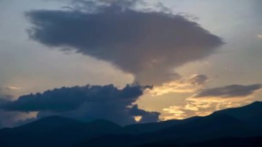 Ermenistan 'ın başkenti Dilijan' da günbatımı ışığıyla aydınlanan uçan dramatik bulutların altında yeşil ormanlarla kaplı güzel dağlar. Gün batımında bulutların hareketini gösteren zaman dilimi videosu