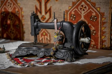 Geleneksel Ermeni eski halı arka planına karşı klasik antika siyah metal elle dikiş makinesi dikişe hazır.