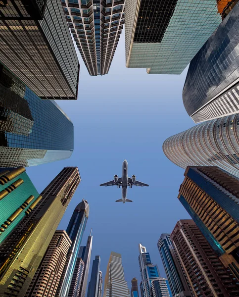 Airplane flying over business skyscrapers of financial center. Travel, economy, cargo, transportation concept. Low wide angle perspective view