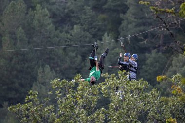 Tsaghkadzor, Ermenistan - 03 Eylül 2023: Zip hattı çalışanı çiftin platforma çıkmasına yardım ediyor. Seçici odak, bulanık arkaplan