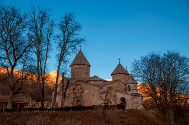 Haghartsin Manastırı (13. yüzyıl) gün batımında Dilijan, Ermenistan 'da güneş ışığı dağları tarafından aydınlatılır.