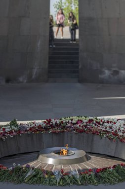 Tanımlanamayan kızlar, Ermeni Soykırımı Anıtı 'ndaki Ebedi Alev' de, Tsitsernakaberd, Erivan, Ermenistan 'daki renkli çiçeklerle çevrili bulanık arka planda yas tutuyorlar.