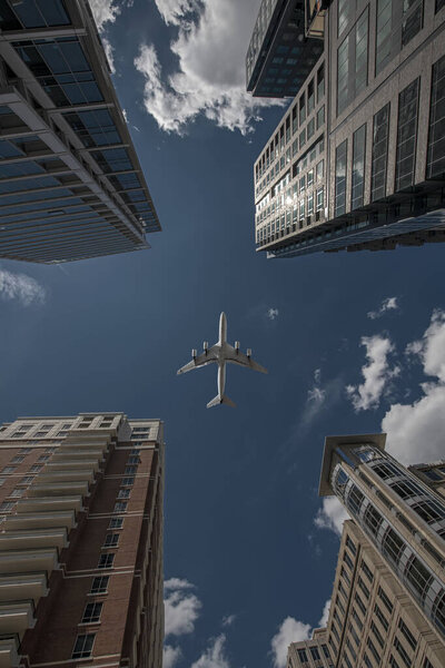 Самолет пролетает над деловыми небоскребами финансового центра. Концепция путешествий, экономики, грузов, транспорта. Вид с низкого угла