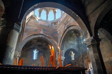 Ön planda yanan mumlarla Hovhannavank Manastırı 'nın (13. yüzyıl) alçak açılı görüntüsü. Ermenistan 'ın Aragatsotn ilindeki Ohanavan köyünde yer almaktadır. Mumlara odaklan.