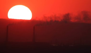Güneş, Kazakistan 'daki Almaty 2 Termik Santrali' nin bacalarının üzerinde batıyor..