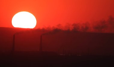 Güneş, Kazakistan 'daki Almaty 2 Termik Santrali' nin bacalarının üzerinde batıyor..