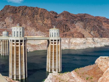 Hoover Barajı köprüsü kayalık bir kanyona yayılıyor, Colorado Nehri ve arka planda açık mavi gökyüzü var.