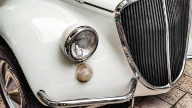 Yuvarlak far ve krom ızgaralı klasik beyaz araba.