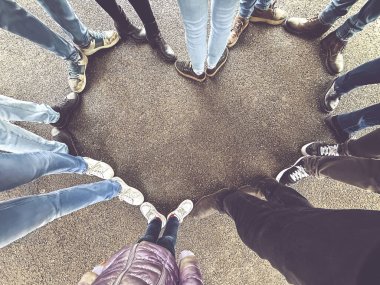 Ayakları kalp şeklinde bir alan oluşturan, birlik ve dostluğu sembolize eden, bir grup insanın daire içinde durduğu bir tepeden çekim..