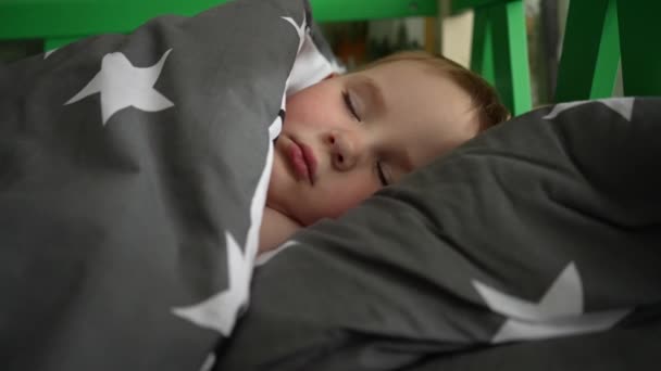 ハンサムな男の子はカバーの下のベッドで眠る ビデオを閉じます — ストック動画