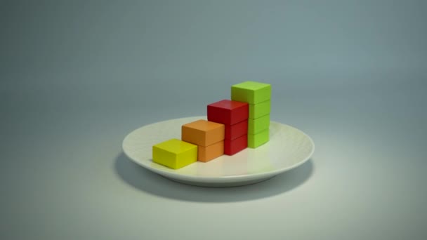 ホワイトプレート上の4つの異なる色の財務チャートを成長させました 木の立方体からの成長チャートです 食品やパン屋の成長 増加または成功のテーマ — ストック動画