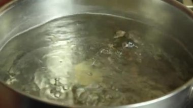 Ukrainian national dish. The process of making dumplings. The woman's hand throws the dumplings one by one into the boiling water in the pan. Close-up.