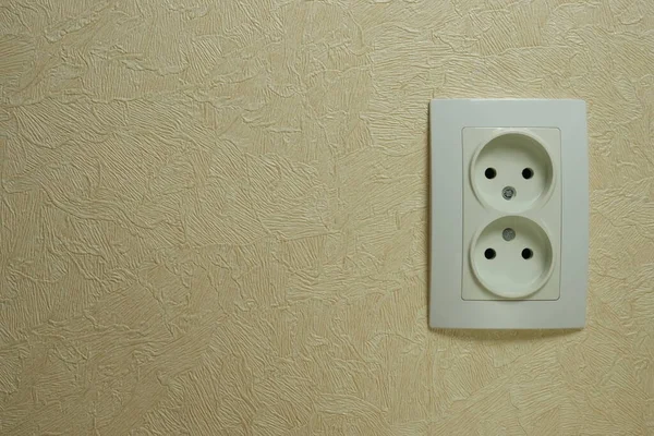 Double white plastic electrical socket on the wall. Place for text.