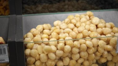 Peeled macadamia nut kernels close-up on the store counter. Macadamia close-up in a transparent container. Panorama. Healthy food concept, storage and sale of nuts