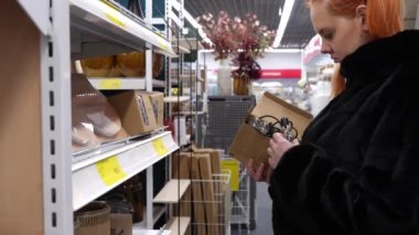 A girl in a store selects and examines an electronic wireless garland of small light bulbs. Energy saving concept. Modern technologies. general plan