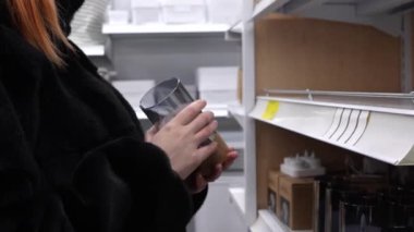 Mağazadaki hamile bir kız elektronik mumu inceliyor. Enerji tasarrufu kavramı. Modern teknolojiler. Pilli mum. Yakın plan. Tanımlanamaz.