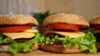 Three fresh juicy meat burgers with cheese on a wooden board close-up. The process of making burgers. Panorama.