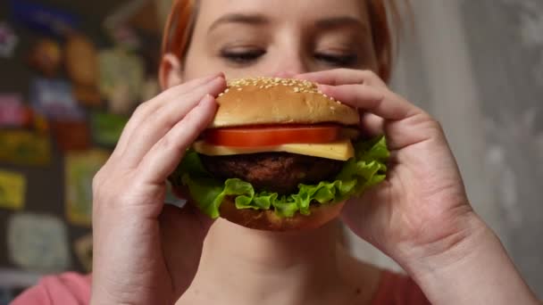 女の子の近くの手の中にジューシーな肉バーガー 焦点を当てた女の子はハンバーガーをかむとその味を楽しむ — ストック動画