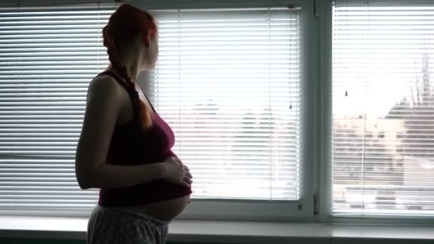 出産を見越して病院にいた妊婦が窓から外を眺め 胃を撫でている 母親の経験 高品質4K映像 — ストック動画
