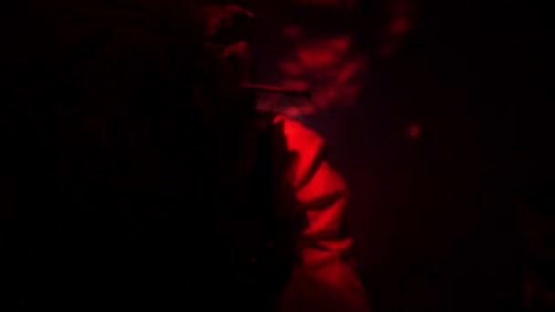 一个戴着邪恶生物的可怕面具的男人红色闪烁的光 暮暮一个手靠近脸的人脸上戴着恶魔面具 优质Fullhd影片 — 图库视频影像