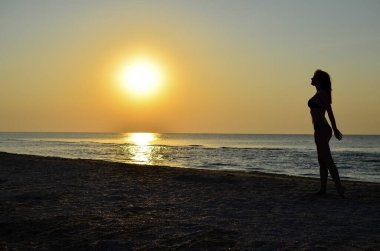 Güzel genç bir kız deniz kıyısında yürüyor.