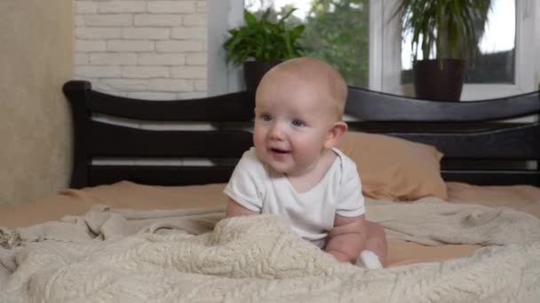 Baby Sits Hesitantly Bed Smiles Playfully Little Boy White Bodysuit — Stock Video