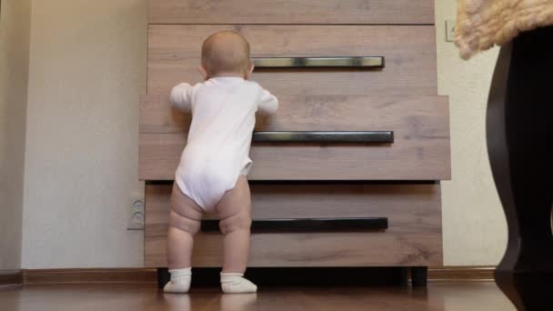 Little Boy White Bodysuit Socks Stands Chest Drawers Tries Open — Stock Video