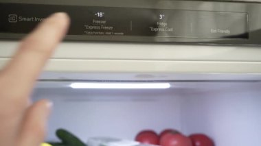 Bir erkeğin eli buzdolabı ve dondurucunun ısısını ayarlar. Yakın plan. Modern gri stil buzdolabı. Uygun yiyecek depolama sıcaklığı. Yüksek kalite 4k görüntü