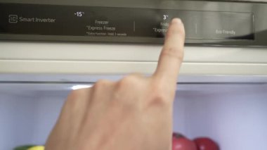 Bir erkeğin eli buzdolabı ve dondurucunun ısısını ayarlar. Yakın plan. Modern gri stil buzdolabı. Uygun yiyecek depolama sıcaklığı. Yüksek kalite 4k görüntü