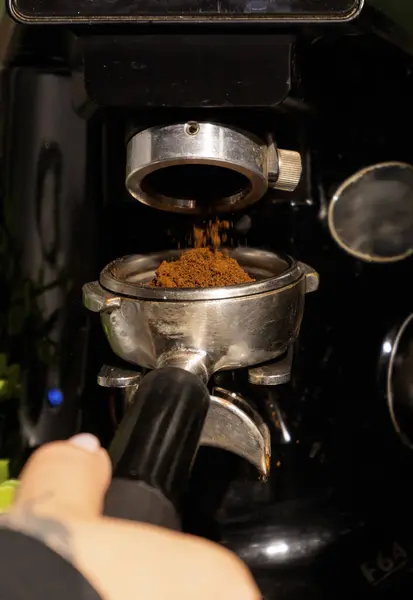 Kahve öğütücü kahve makinesinin filtresine taze öğütülmüş kahve koyar. Yakın plan. Dikey fotoğraf. Profesyonel espresso hazırlama süreci.