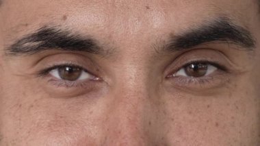 Neşeli erkek doğulu kahverengi gözler yakın plan. Adam doğrudan kameraya bakıyor. Ağır çekim. Yüksek kalite 4k görüntü
