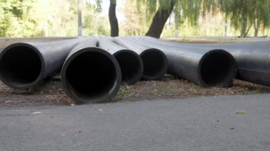 Büyük plastik borular dışarıda yerde yatıyor. Sondan bak. Kanalizasyon boruları, su boruları, ısıtma boruları. Yüksek kalite 4k görüntü