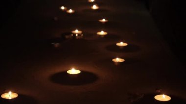 Karanlıkta yanan bir sürü mum. Siyah bir odada yanan küçük mumların yolu. Yeni hayat kavramı, yeniden doğuş, ölüleri hatırlama. Yüksek kalite 4k görüntü