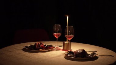 Romantik bir randevuda iki sevgili için alışılmadık bir yuvarlak masa. İki kalp plaka üzerinde kırmızı bir aşk çizgisi ile birbirine dolanır. Mum ışığında iki kişilik yemek. Dehşet. Yüksek kalite 4k görüntü