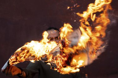 Sakallı, siyah saçlı bir adam önünde yanan bir gazete tutuyor. Elinde yanan bir kağıtla duvara yaslanmış tehditkar bir adamın portresi. Yüksek kalite fotoğraf