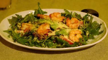 Aperatif roka salatası, avokado ve yuvarlak tabakta karides. Restoran servisi. Loş ışık. Kapatın. Yüksek kalite 4k görüntü
