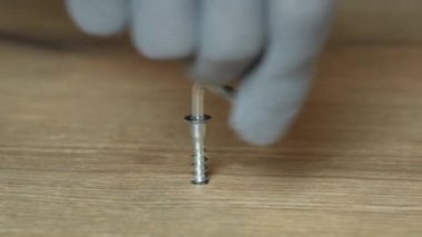 Adamın eli, onayı onaylamak için tahta panoya büyü anahtarı takıyor ve deliği özel bir tıkaçla kapatıyor. Marangozlar iş eldivenlerini yakın plan çekiyorlar. Yavaş çekim. 
