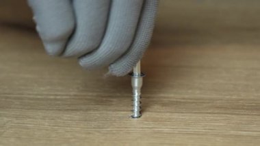 Adamın eli, onayı onaylamak için tahta panoya büyü anahtarı takıyor ve deliği özel bir tıkaçla kapatıyor. Marangozlar iş eldivenlerini yakın plan çekiyorlar. Ağır çekim. 4k